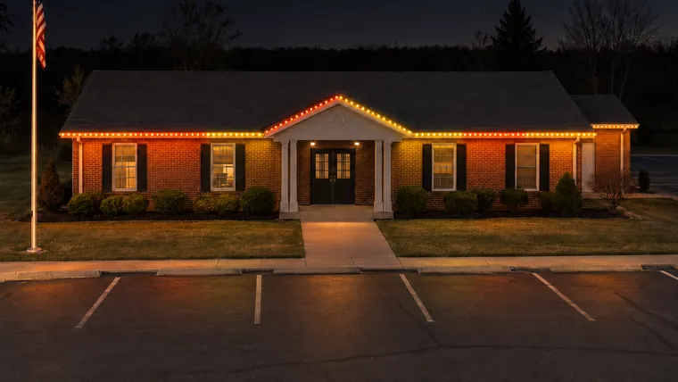 A township hall at night with permanent roofline lighting set to harvest