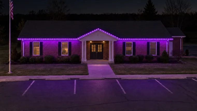 A township hall at night with permanent roofline lighting set to purple