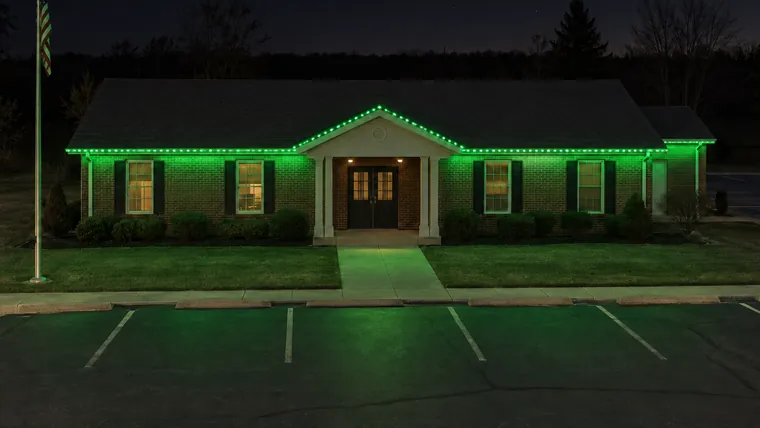 A township hall at night with permanent roofline lighting set to st. patrick's