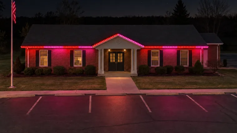 A township hall at night with permanent roofline lighting set to valentine's