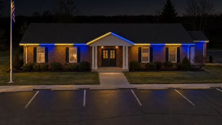 A township hall at night with permanent roofline lighting set to wolverines